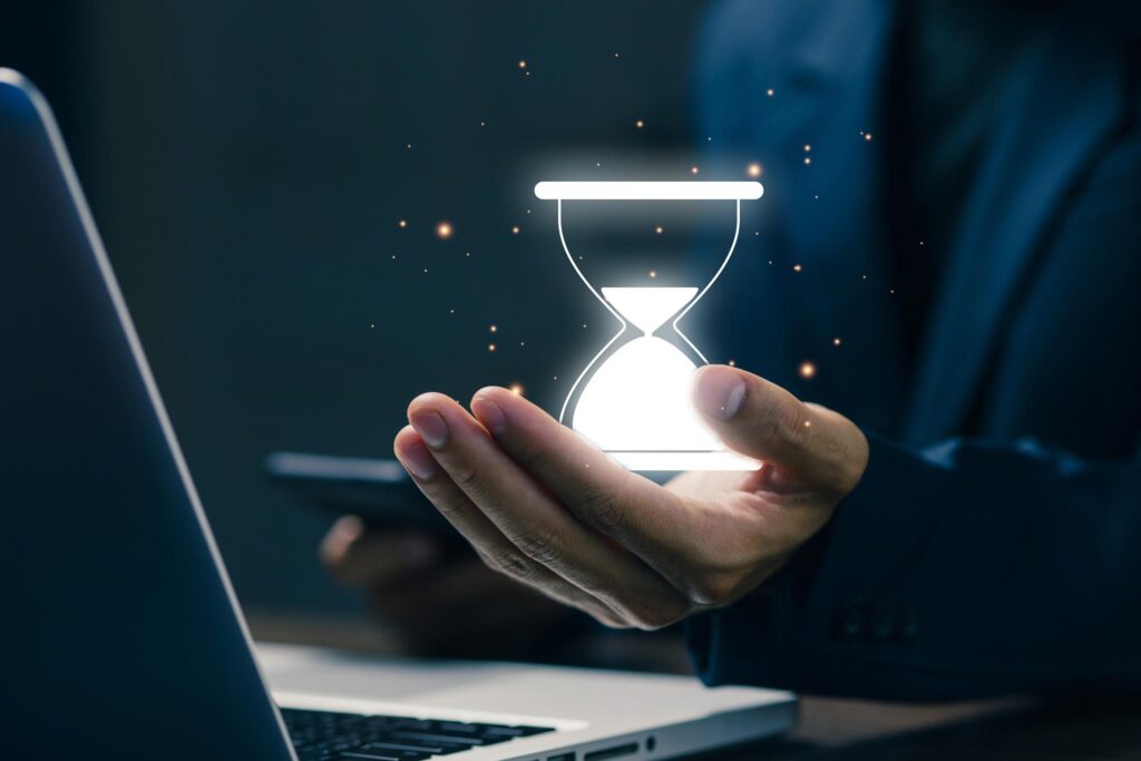 Ampulheta digital brilhando nas mãos de um executivo ao lado de notebook, representando gestão do tempo, produtividade e equilíbrio profissional.